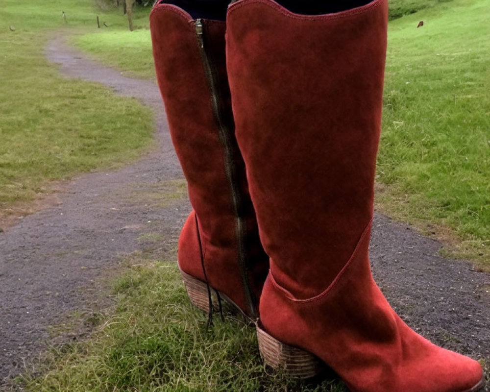 Person in Red Suede Knee-High Boots on Grass Path