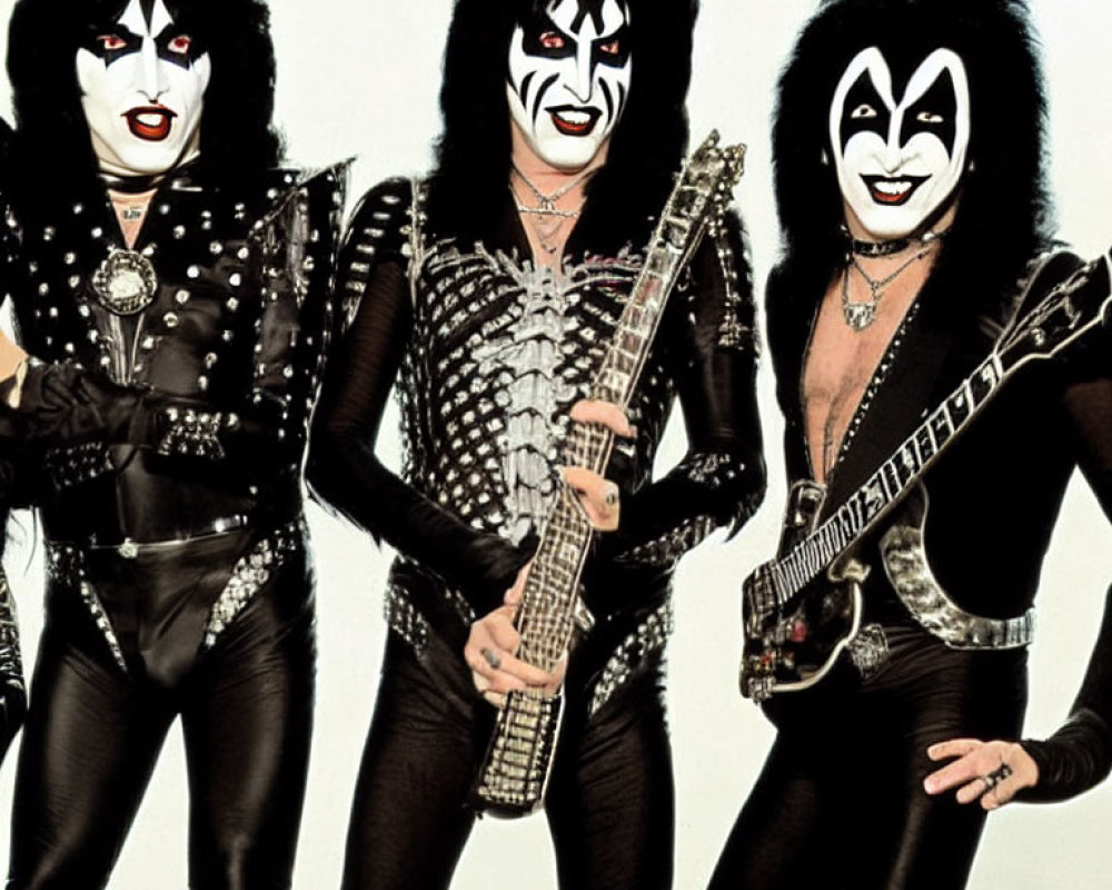 Three individuals in black and silver stage outfits with face paint - promotional photo.