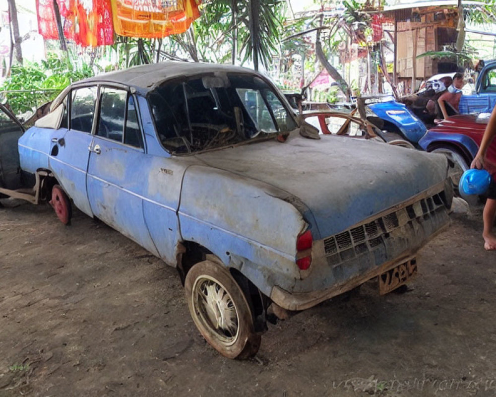 Weathered Blue Car with Missing Wheel in Tropical Setting