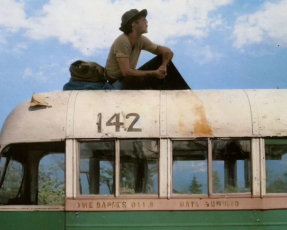 Person sitting on vintage bus number 142 under clear sky