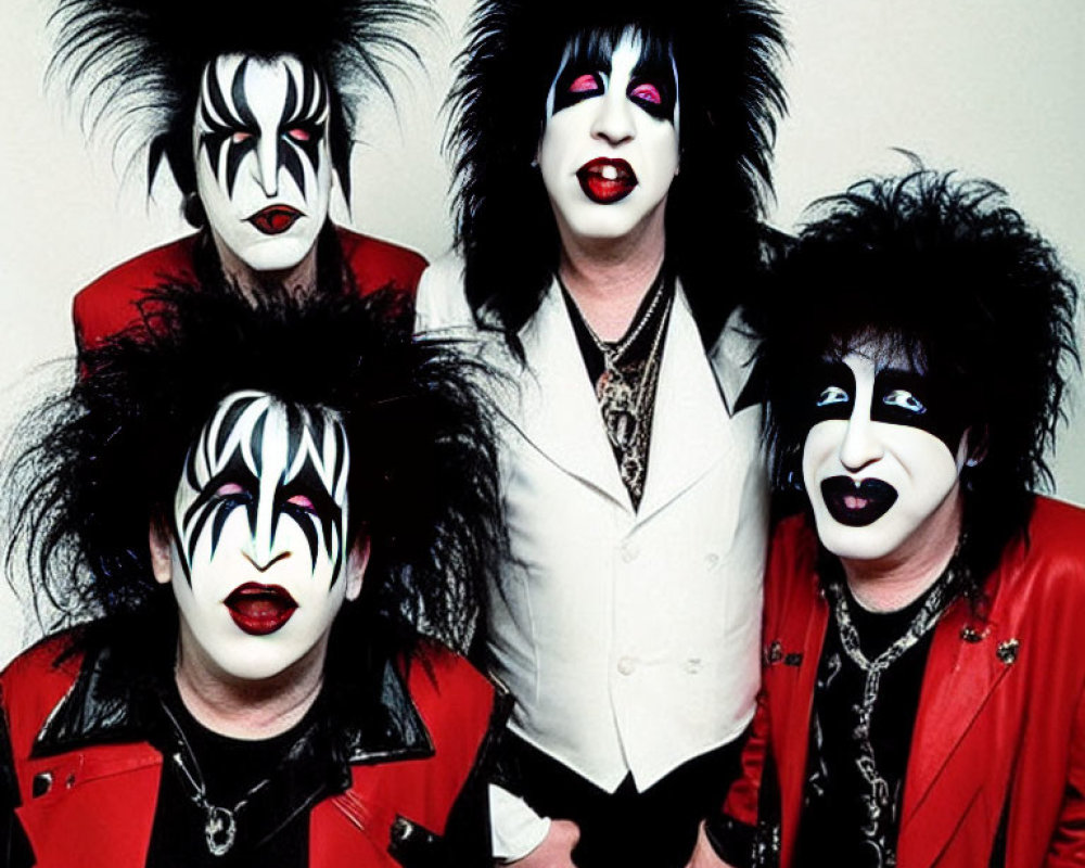 Four individuals in black and white face paint with wild black hair, dressed in rock-inspired attire.