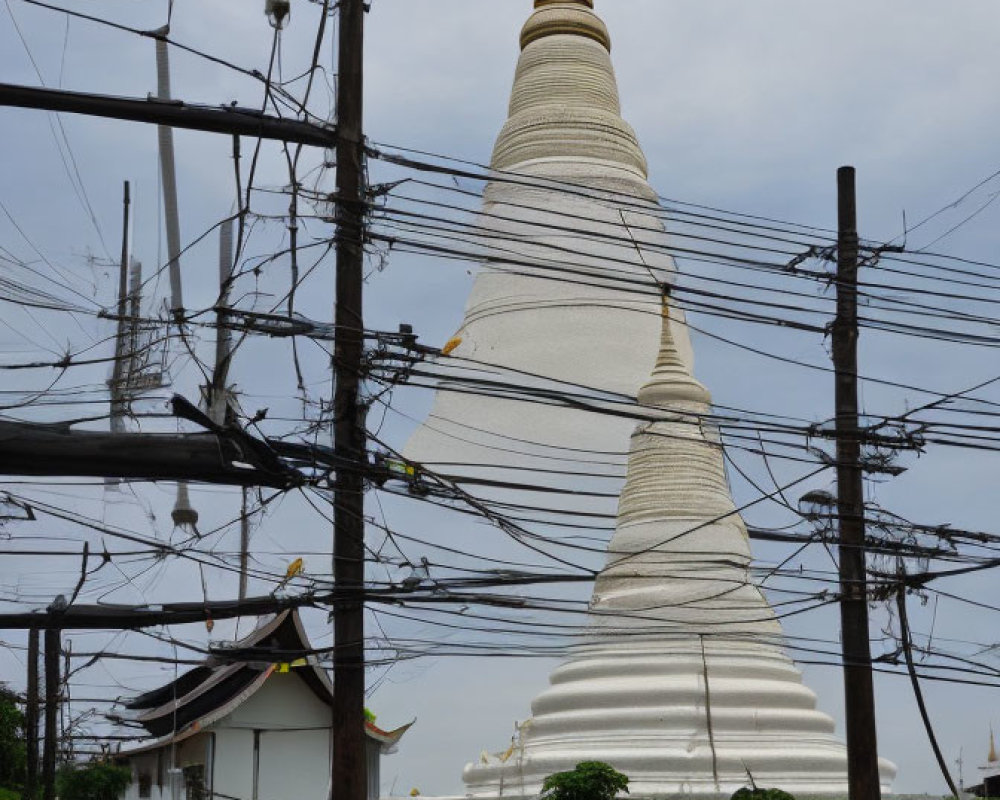 Buddhist stupa with power lines, car, and building in scene