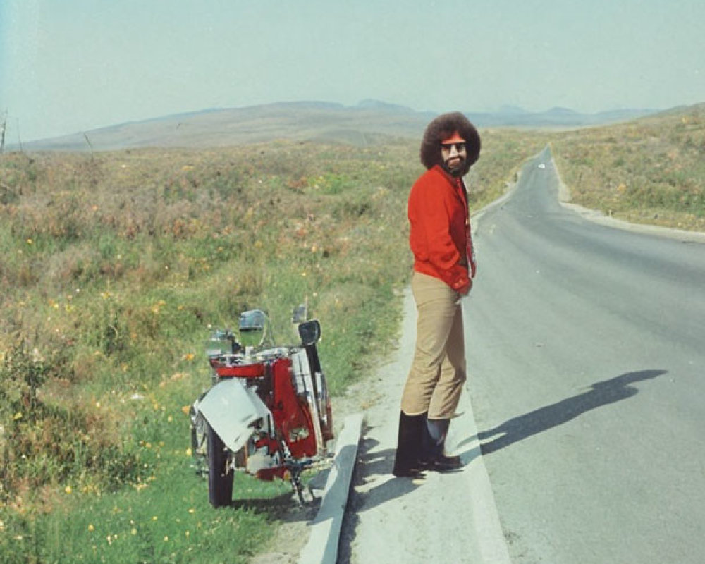 Person with Afro Hairstyle Next to Motorcycle on Open Road