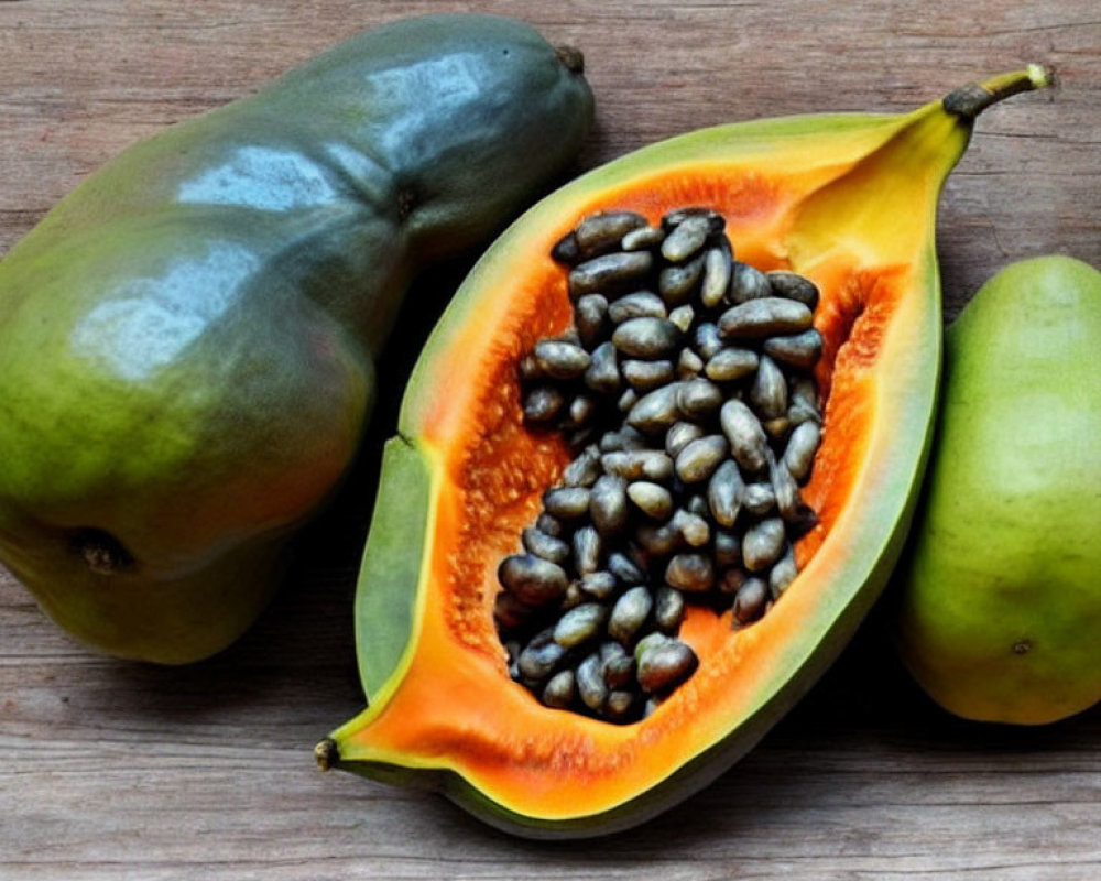 Fresh Papaya Whole and Sliced with Black Seeds on Wooden Surface