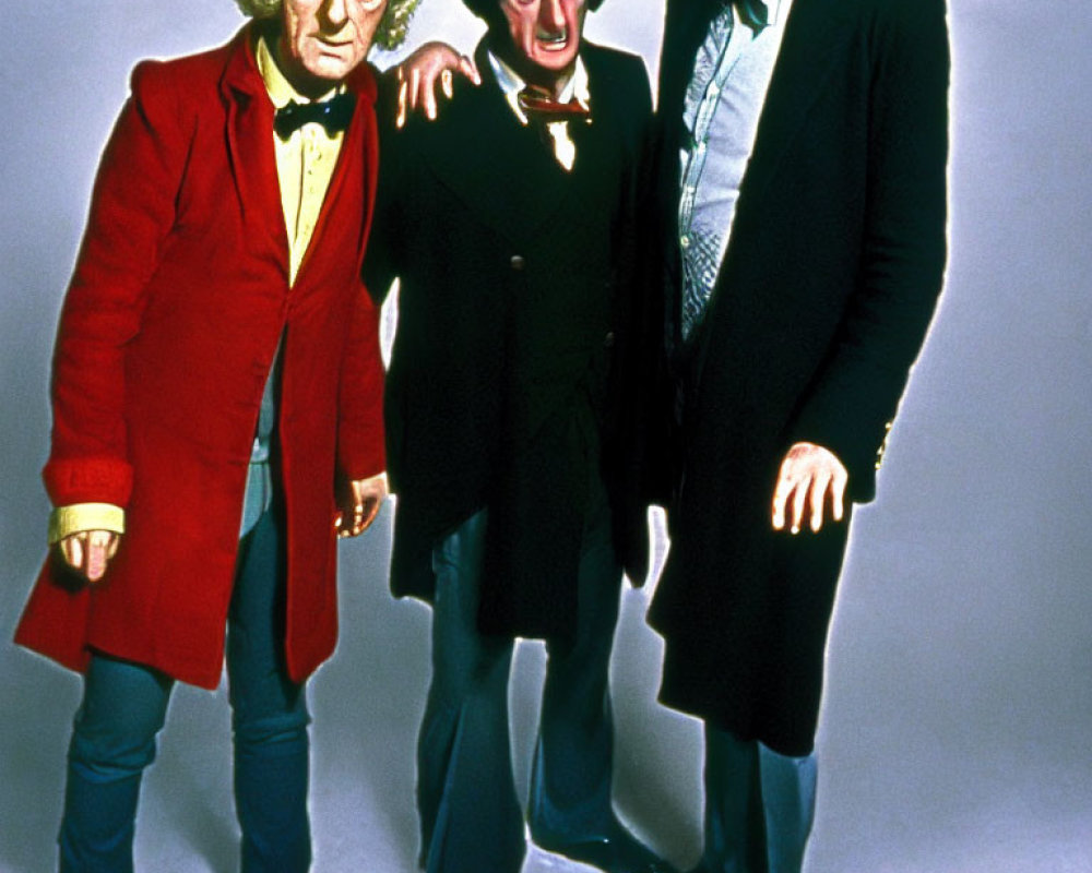Three men in colorful costumes: red coat, black coat with ruffled shirt, and green blazer
