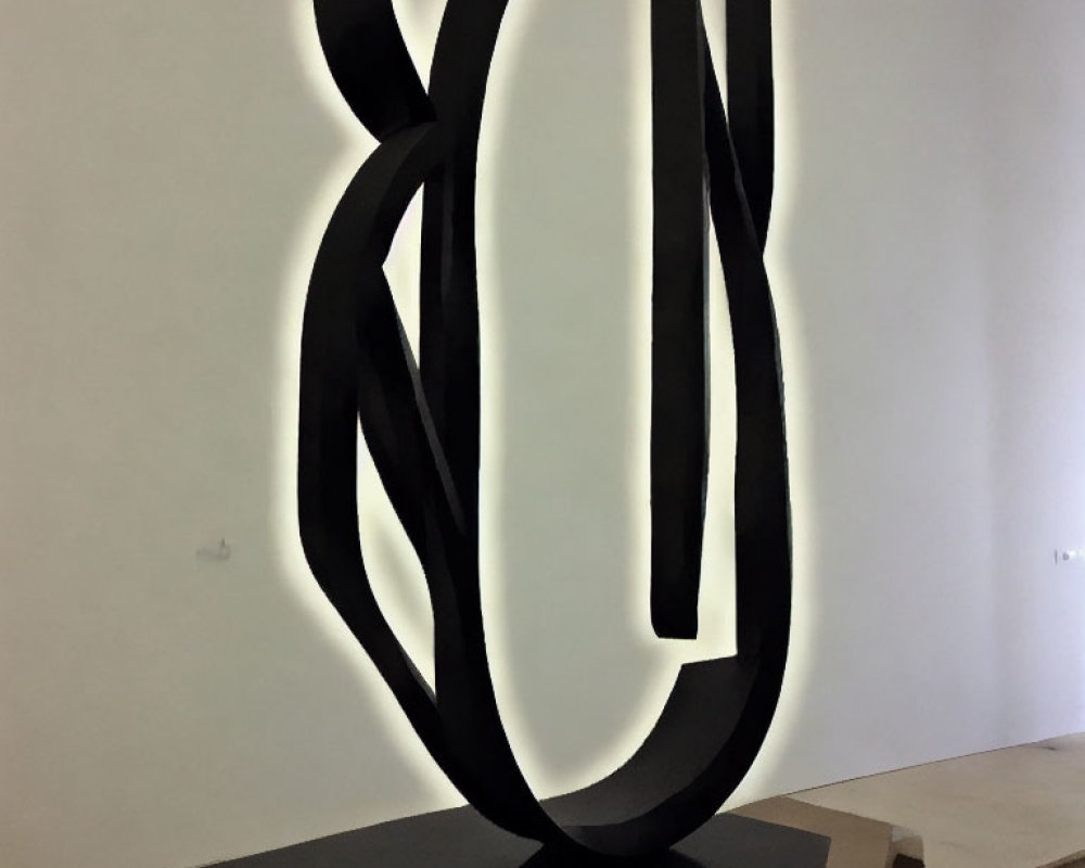 Abstract twisted black sculpture on brown pedestal in gallery display