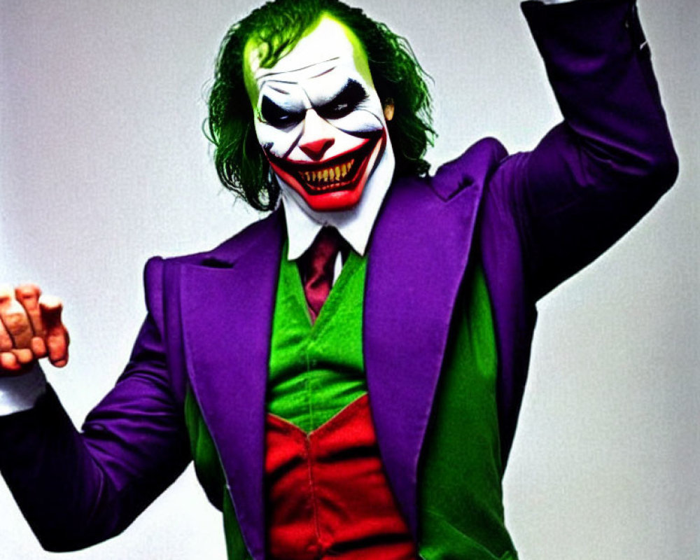 Person in Joker costume with white face paint and green hair striking dramatic pose
