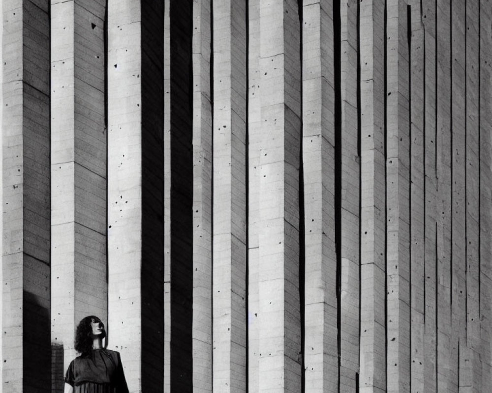 Woman Standing Before Large Wall with Concrete Stripes and Shadows