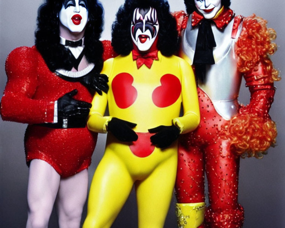 Three individuals in flamboyant costumes with exaggerated heart symbols.