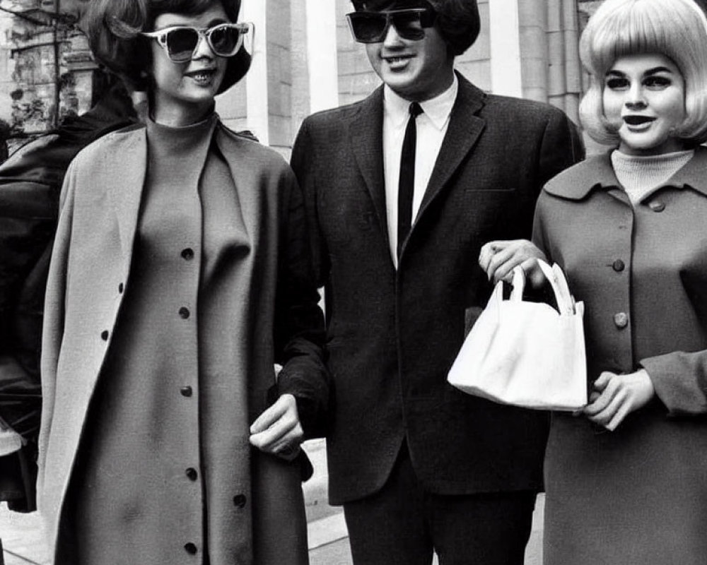 Three individuals in retro fashion with large sunglasses and stylish coats walking confidently.