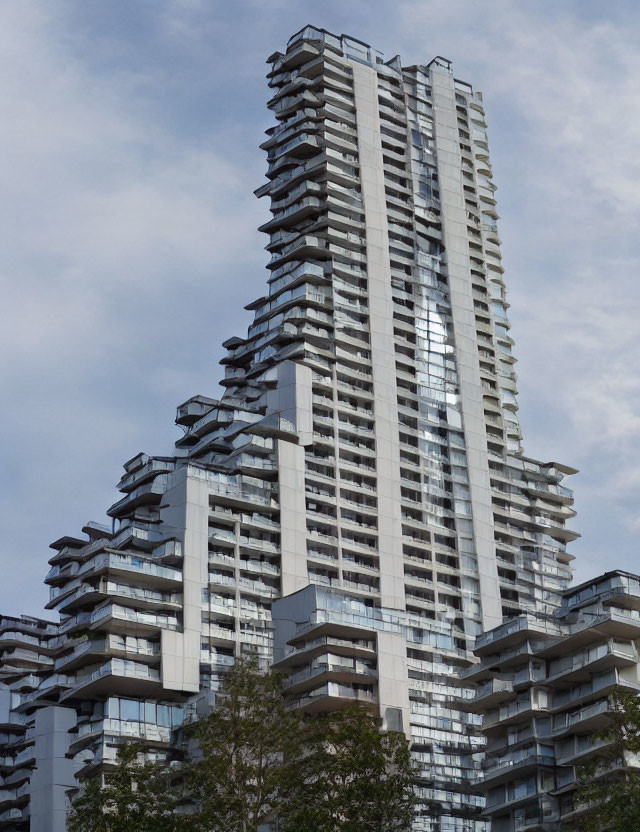 Contemporary high-rise with stacked balconies under cloudy sky