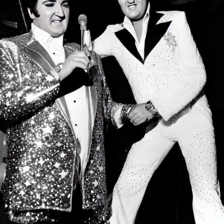 Two Elvis Impersonators in Sparkling Outfits Holding Microphones in Black and White Photo