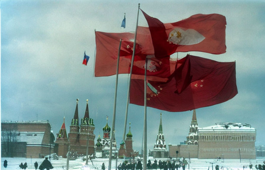 Three flags flying in front of Kremlin and snow-covered ground