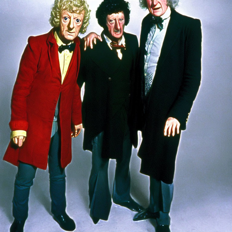 Three men in colorful costumes: red coat, black coat with ruffled shirt, and green blazer