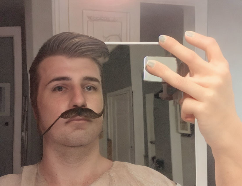 Person holding smartphone with curled mustache, mirrored reflection.