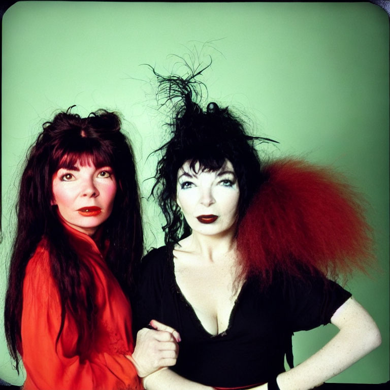 Two women with dramatic makeup and wild hairstyles on green background
