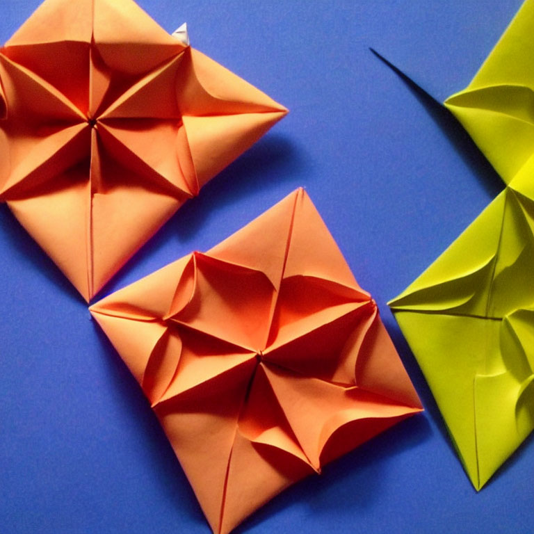 Vibrant paper origami structures on blue background