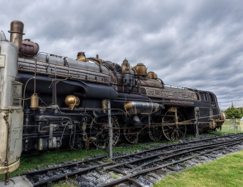 Vintage Steam Locomotive on Tracks with Cloudy Sky Showing Intricate Design and Metallic Textures
