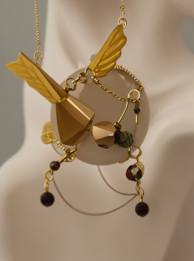 Golden Wing Pendant with Geometric Shapes and Dangling Beads on Mannequin Display