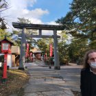 Elderly man in suit at Japanese torii gate with temples and trees