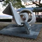 Abstract Grey Concrete Sculpture with Wavy Design and Circular Openings in Park Setting