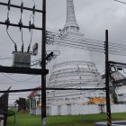 Buddhist stupa with power lines, car, and building in scene
