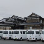 Vintage white vans parked in front of Asian-style building with intricate roofing under overcast sky