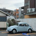 Vintage Light Blue Volkswagen Beetle Parked in Front of Industrial Metal Building