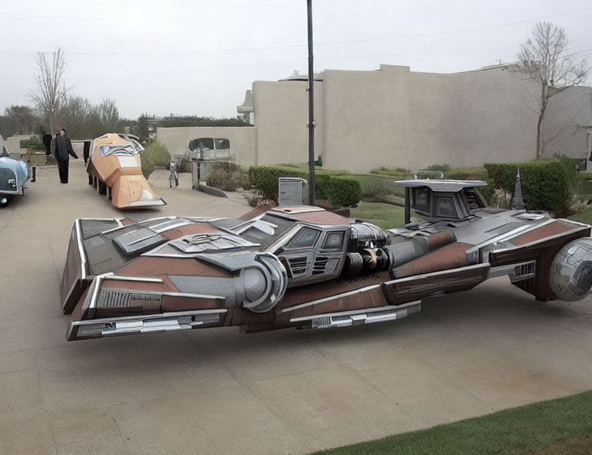Life-sized outdoor display of X-wing fighter spaceship model with person nearby