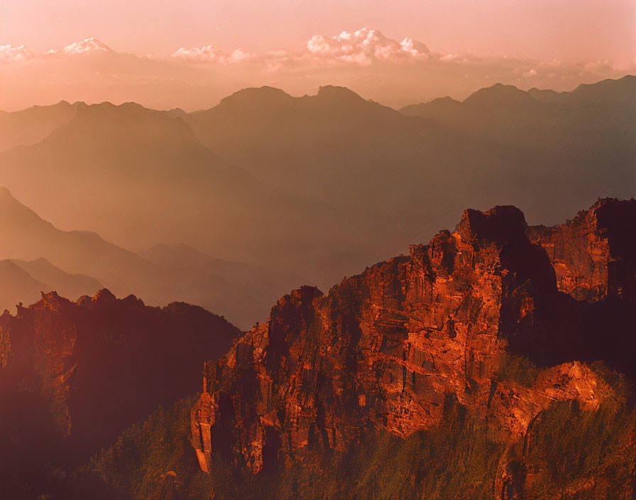 Rugged mountain cliffs at sunset with snow-capped peaks in warm hues