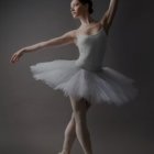 Elegant ballerina in vibrant tutu poses en pointe against dark background