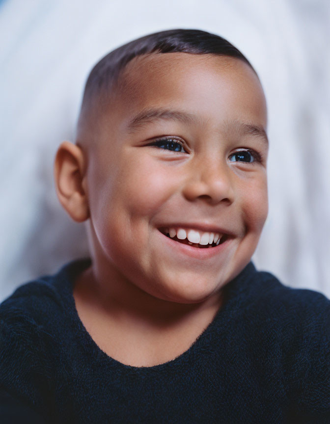 Young boy with crew cut in dark blue shirt on white background