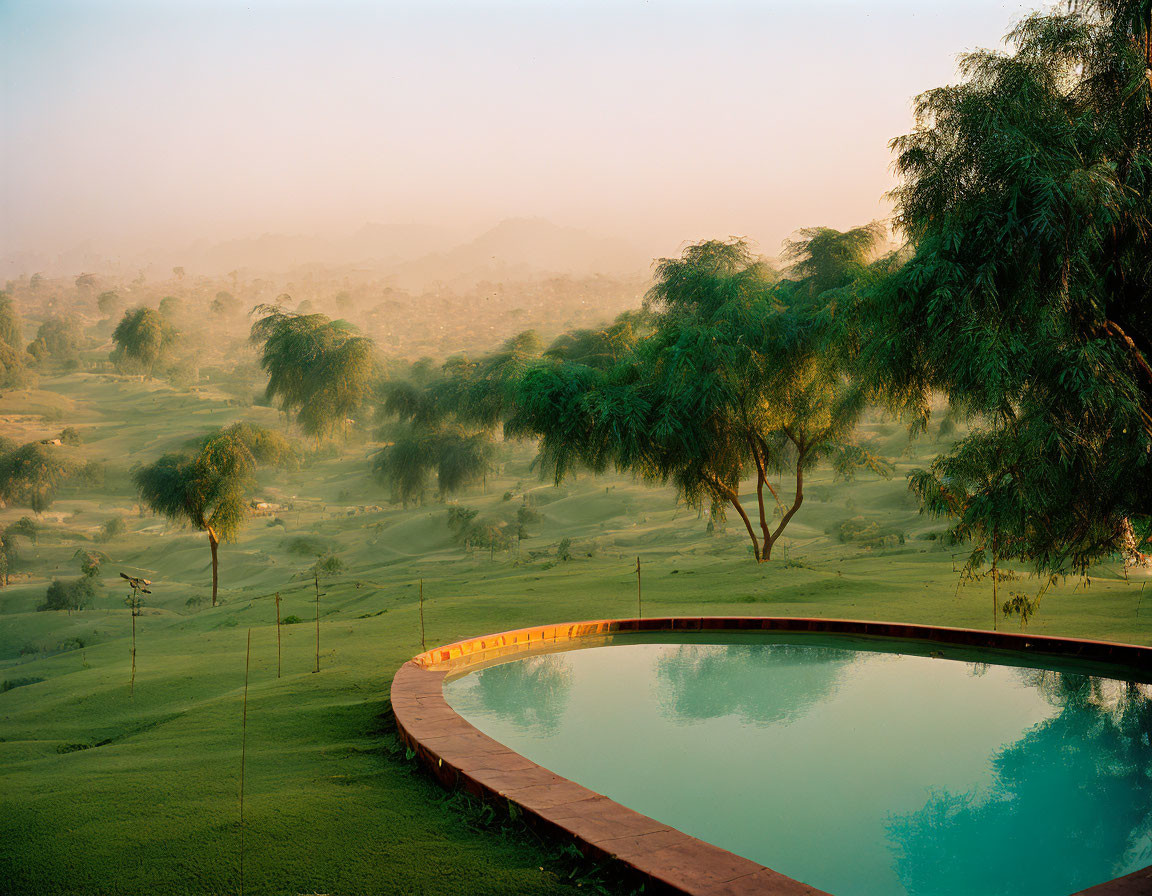 Tranquil sunrise landscape with reflective pool and mist-covered terrain