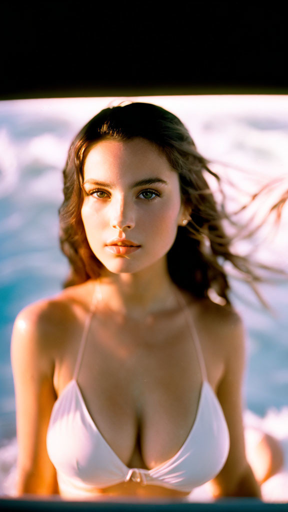 Dark-haired woman in white swimsuit poses by blurred water, sun-kissed skin glowing.