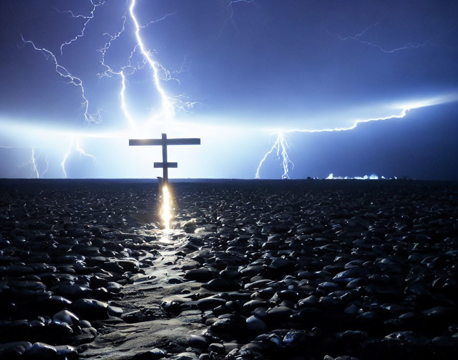 Wooden cross illuminated by lightning on stony ground at night
