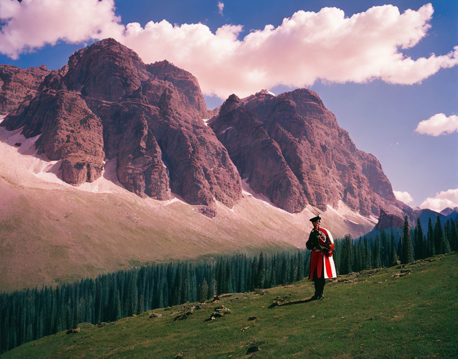 Traditional Attire Figure in Green Field with Mountain Backdrop