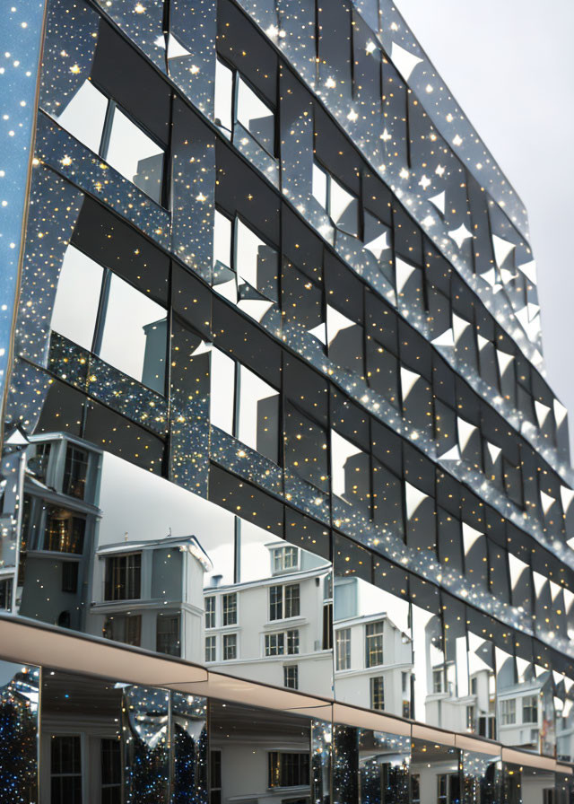 Modern building facade with star-like patterns and reflections against cloudy sky, next to traditional architecture