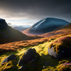 Snow-dusted mountains and moss-covered rocks in rugged valley at sunrise or sunset