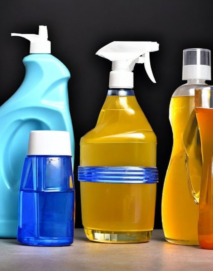 Colorful Cleaning Products in Containers on Dark Background with Blue, Yellow, and Orange Liquids