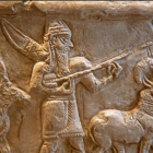 Ancient relief with figures in traditional garb on horseback, detailed interaction, and cuneiform