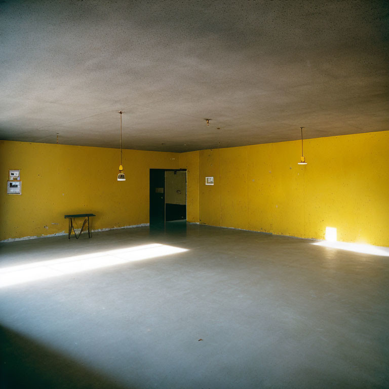 Yellow-walled room with hanging lights, table, black door, and natural light.
