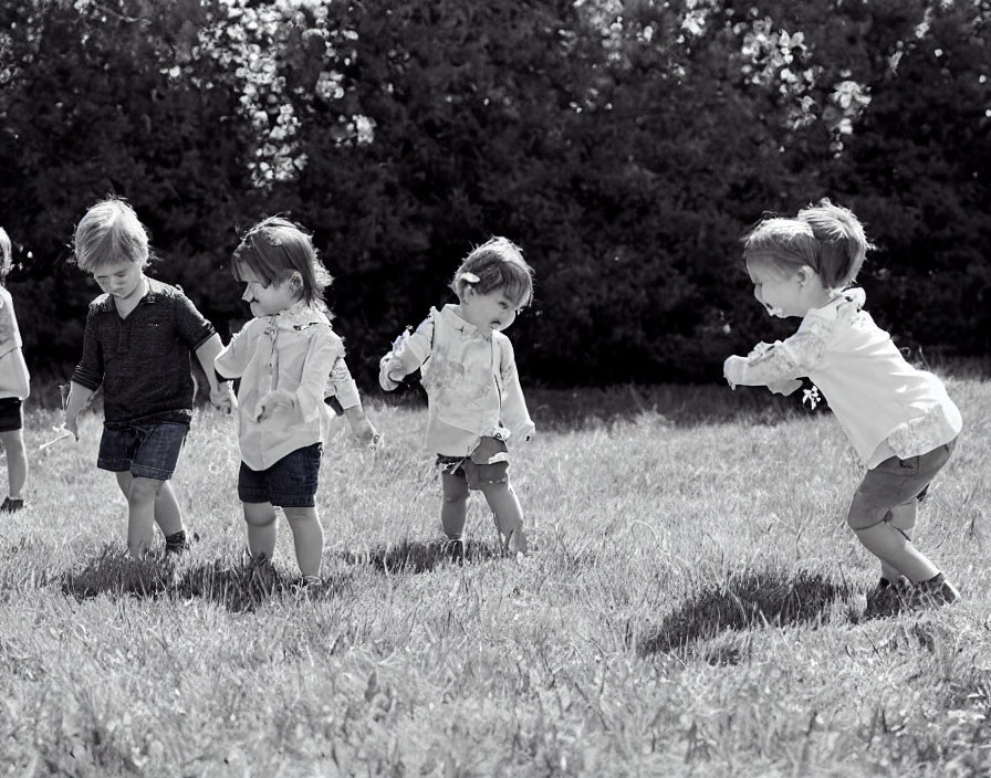 Monochrome image of four kids walking in grassy field
