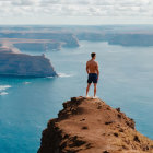 Shirtless man on cliff overlooking vast ocean