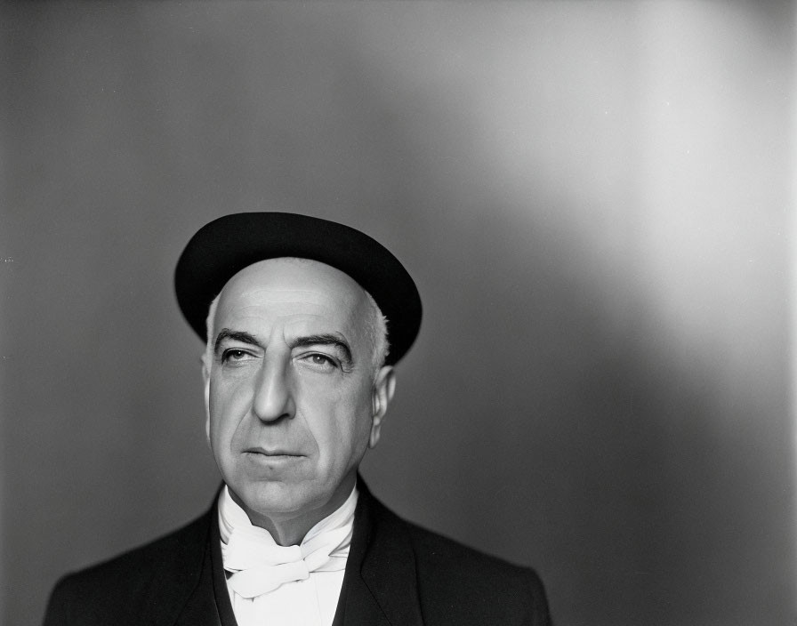 Serious man in bowler hat and tuxedo portrait in black and white