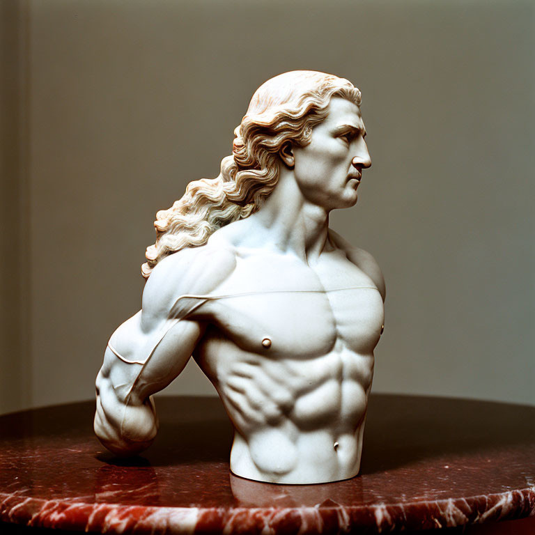Classical-style bust sculpture of a muscular man with flowing hair in warm lighting
