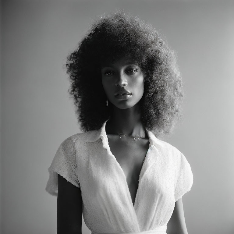 Monochrome portrait of woman with voluminous curly hair in light blouse