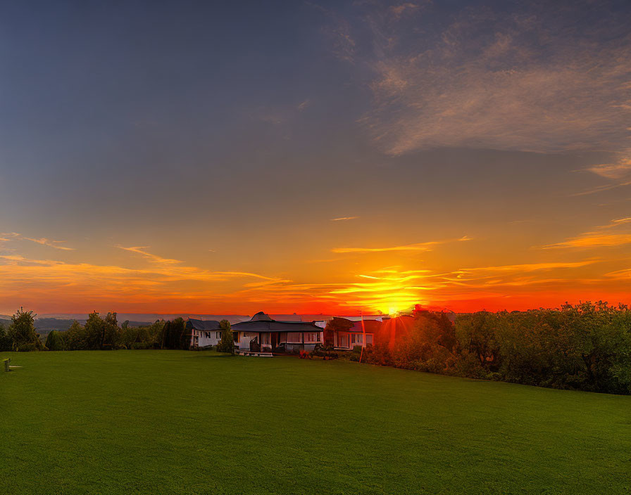 Colorful sunset over large house and green landscape