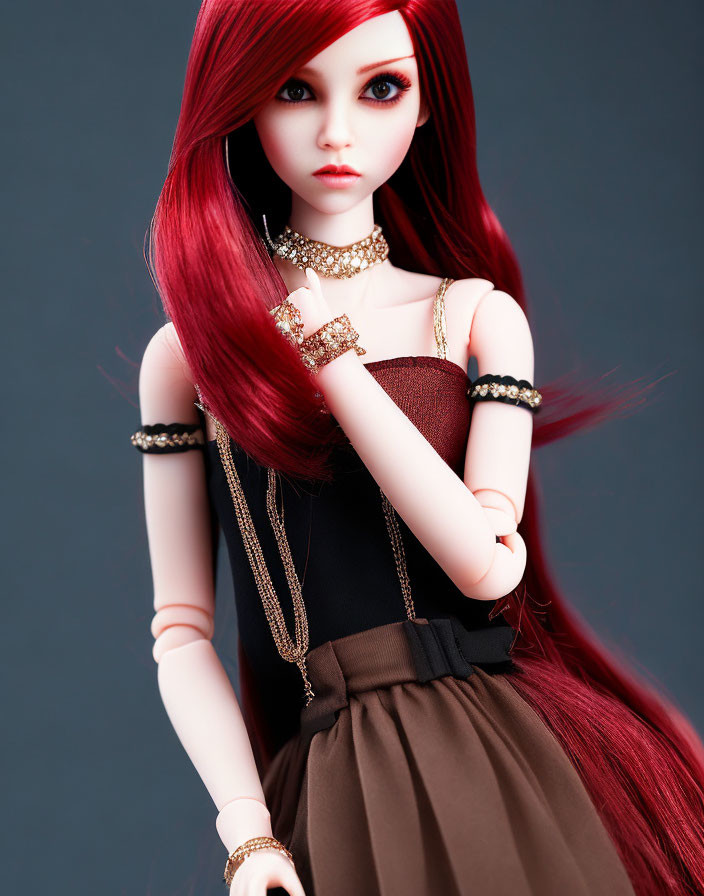 Red-haired doll in black and brown dress with gold jewelry on grey background