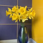 Vibrant watercolor painting of yellow daffodils in blue vase