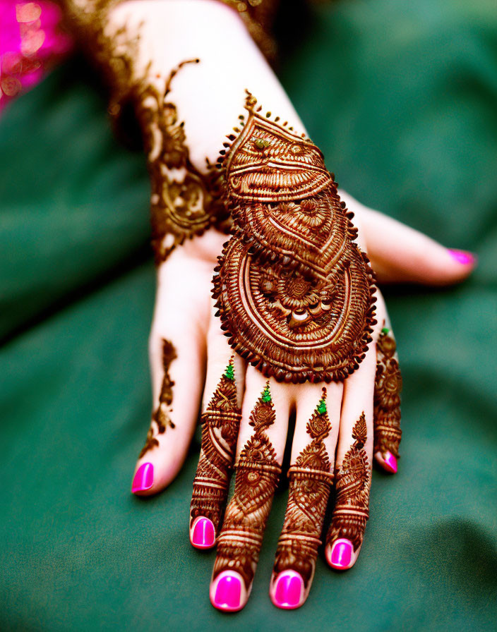 Intricate Henna Hand Design on Green Fabric with Pink Nail Polish